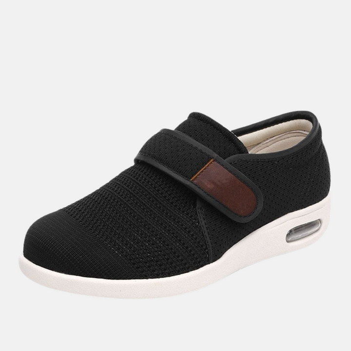 Svart par ortopediska herrsneakers mot ljus bakgrund