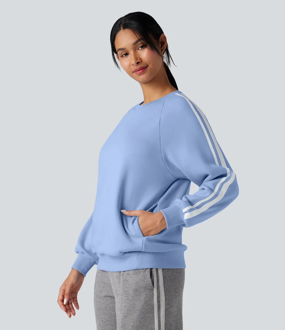 Modell som visar upp de praktiska fickorna på den blå sweatshirt