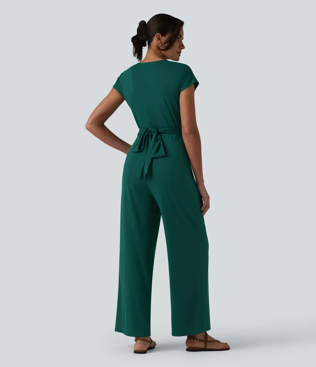 Baksida av grön kortärmad arbetsjumpsuit med knytband i midjan på modell