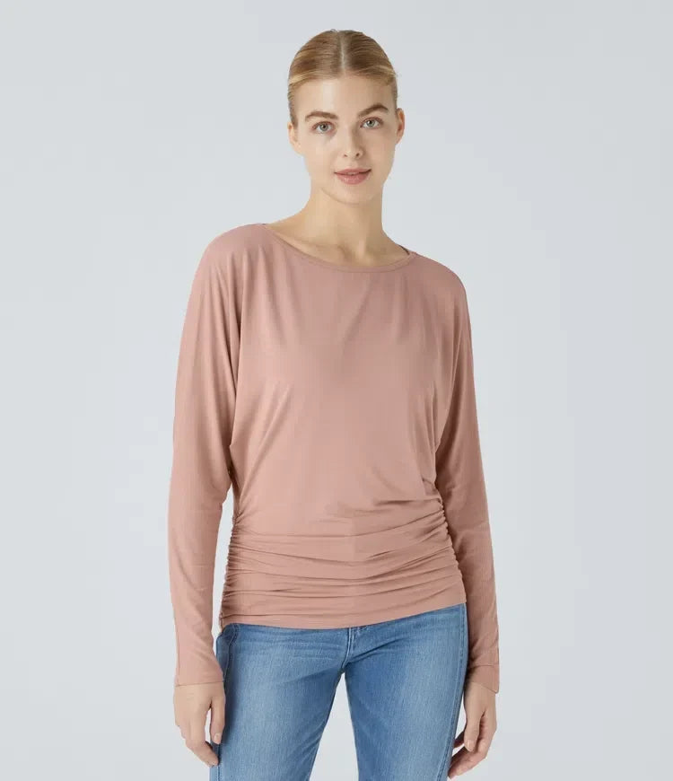 Modell som bär rosa långärmad damtopp med båtringning och rynkade sidor framifrån