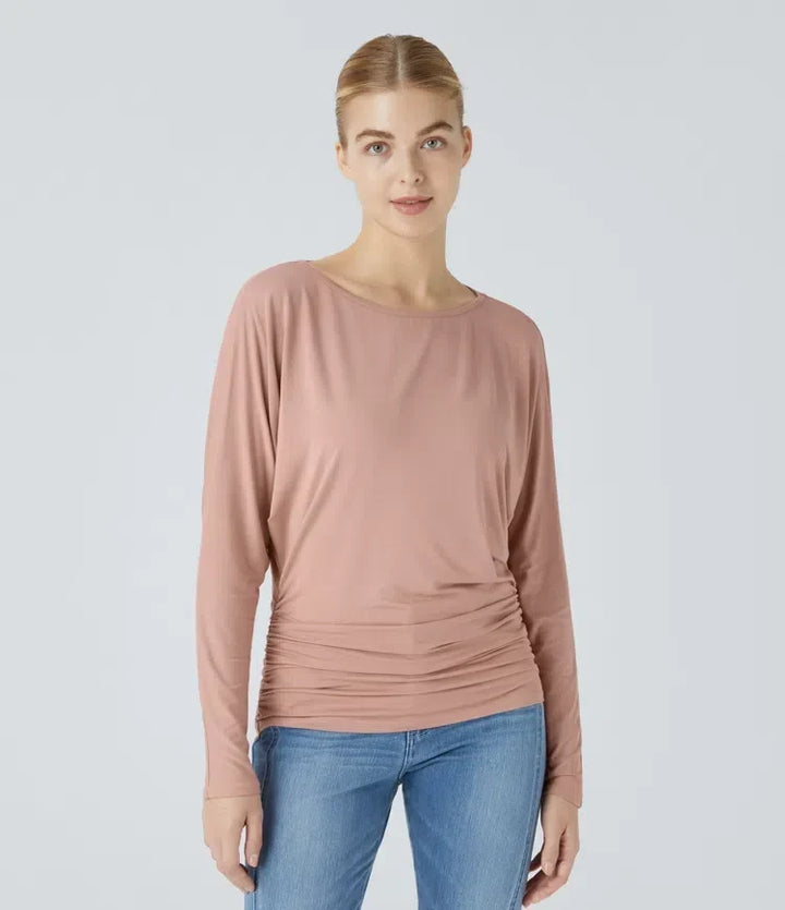 Modell som bär rosa långärmad damtopp med båtringning och rynkade sidor framifrån