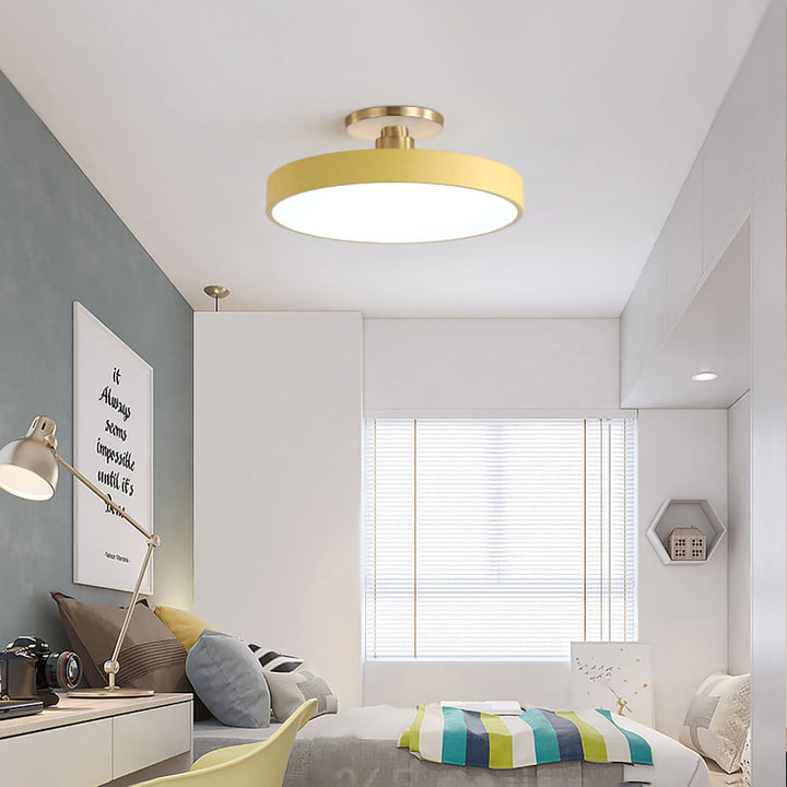 Gul rund LED-taklampa monterad i ett modernt sovrum