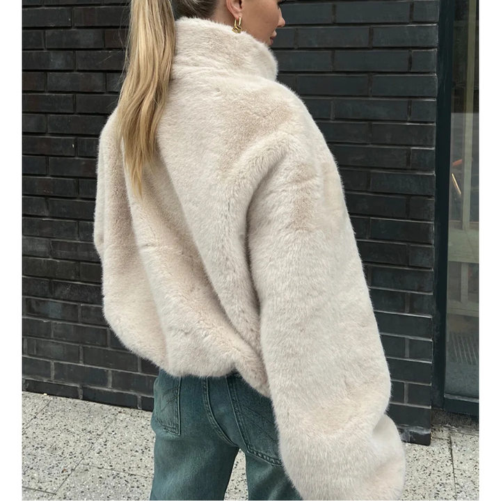 Närbild på struktur och dragkedja på beige dam teddyjacka