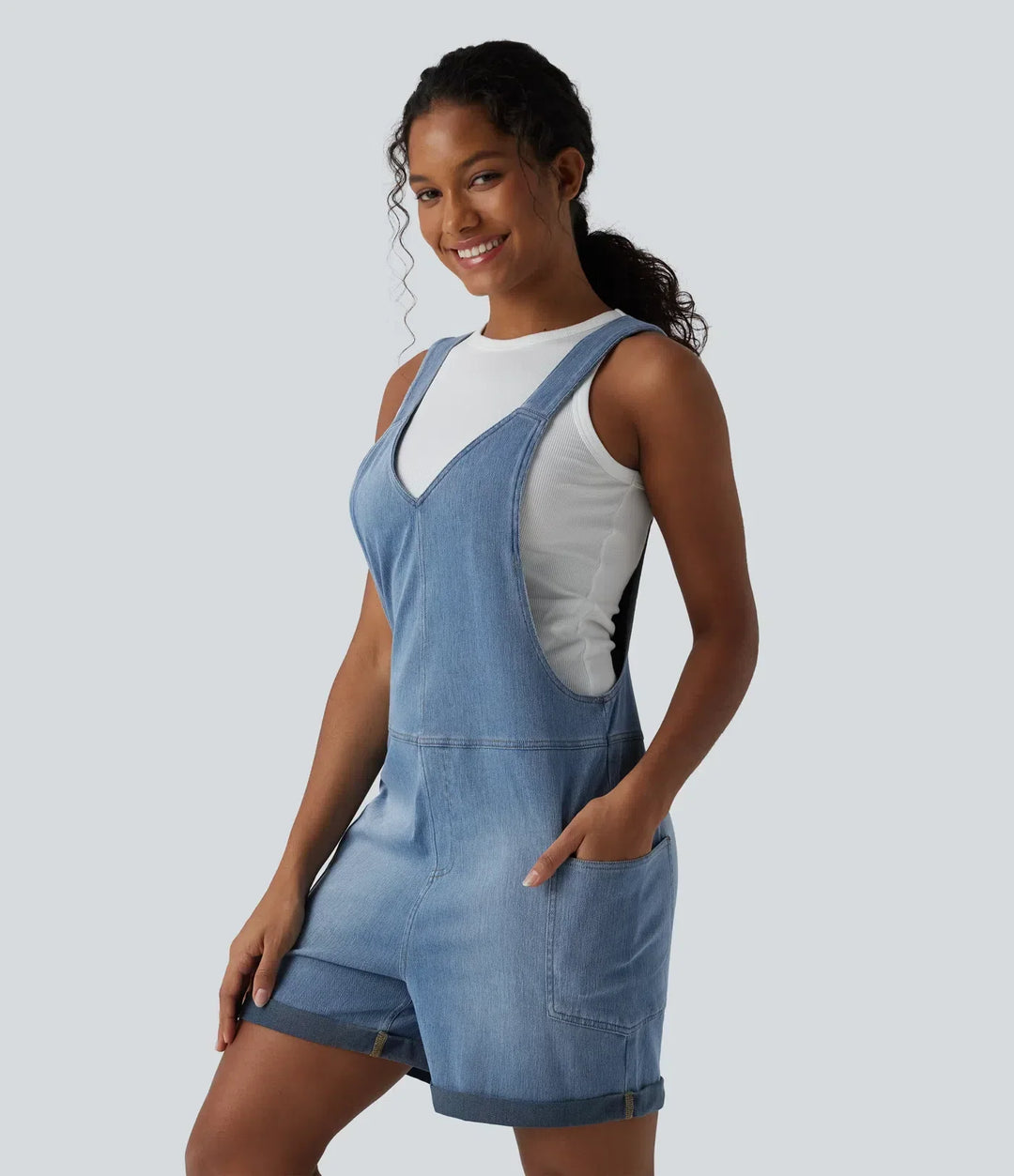 Kort damoverall i ljus denim med V-ringning och praktiska fickor framifrån