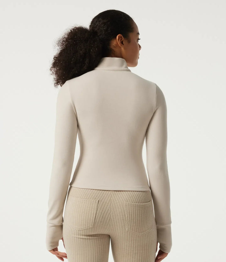 Kvinna i beige långärmad träningsjacka bakifrån
