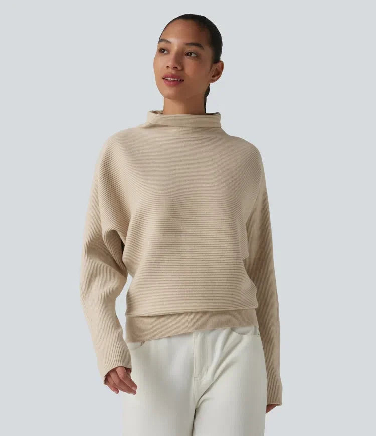 Kvinna iförd beige damtröja med hög hals och fladdermusärm framifrån
