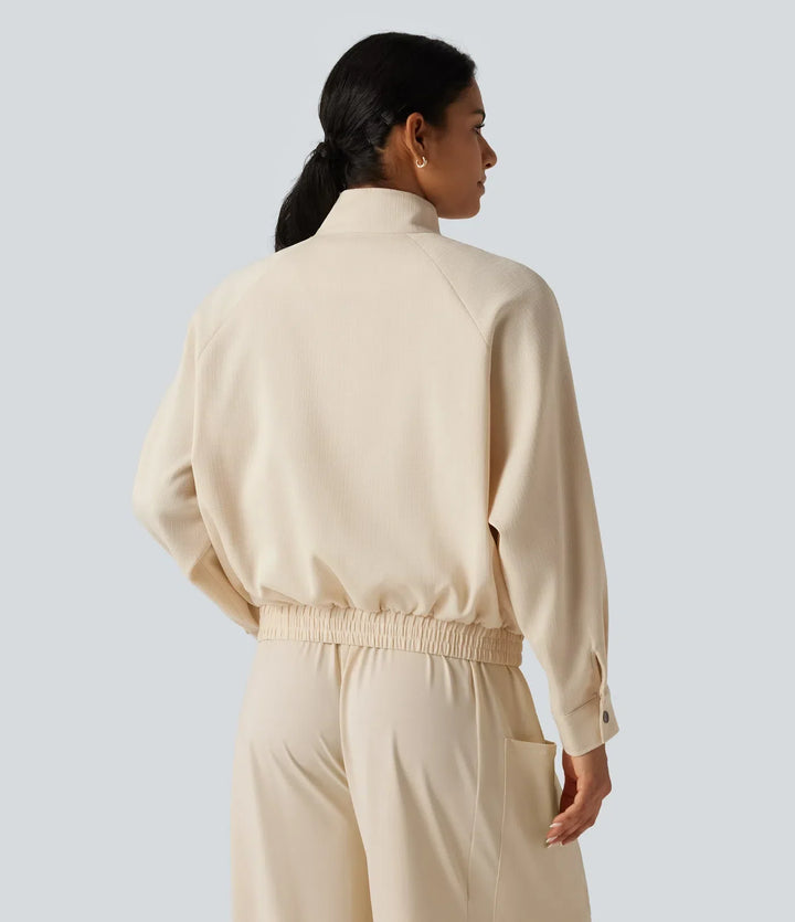 Baksidesvy av beige damjacka med hög krage och elastisk midja