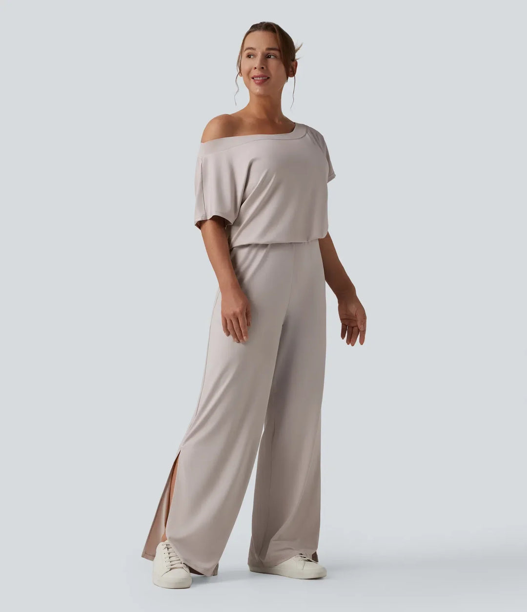 Kvinna stående i enaxlad vardagsjumpsuit med vida ben