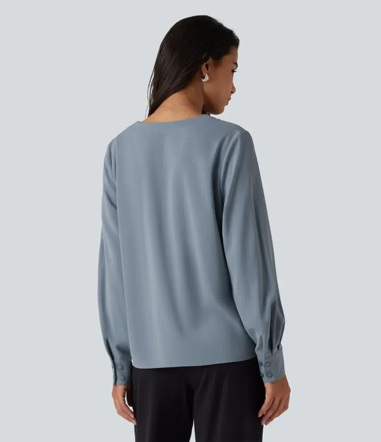 Baksidesvy av dam i elegant blå arbetsblus med knäppta ärmslut