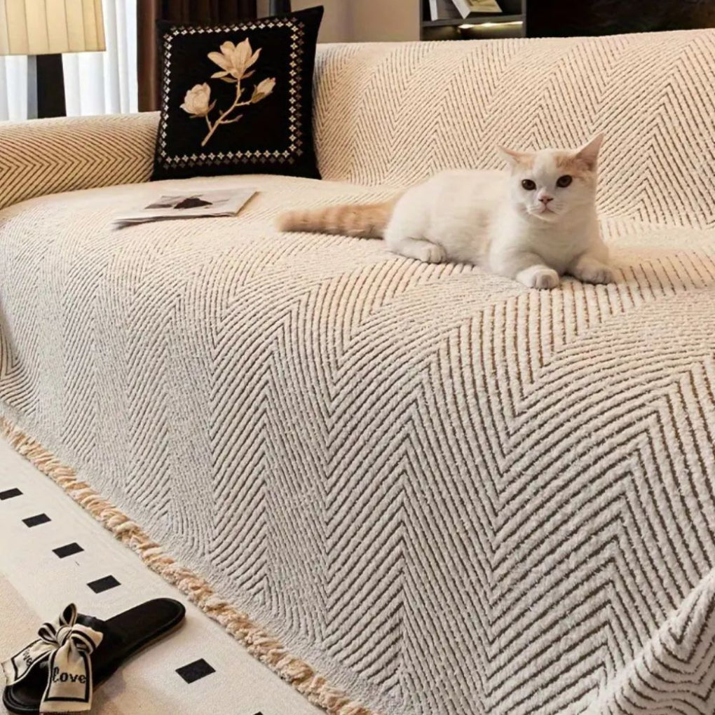 Ljust beigefärgat sofföverdrag med fiskbensmönster och katt i soffan