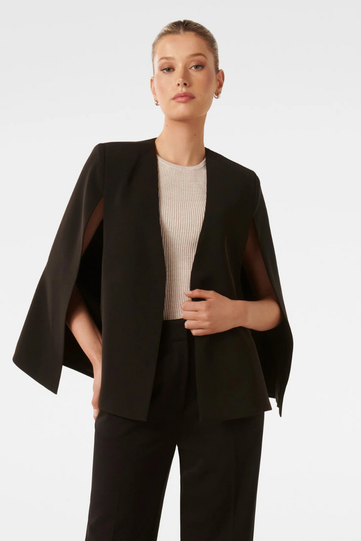 Kvinna i svart elegant cape-jacka med öppna sömmar