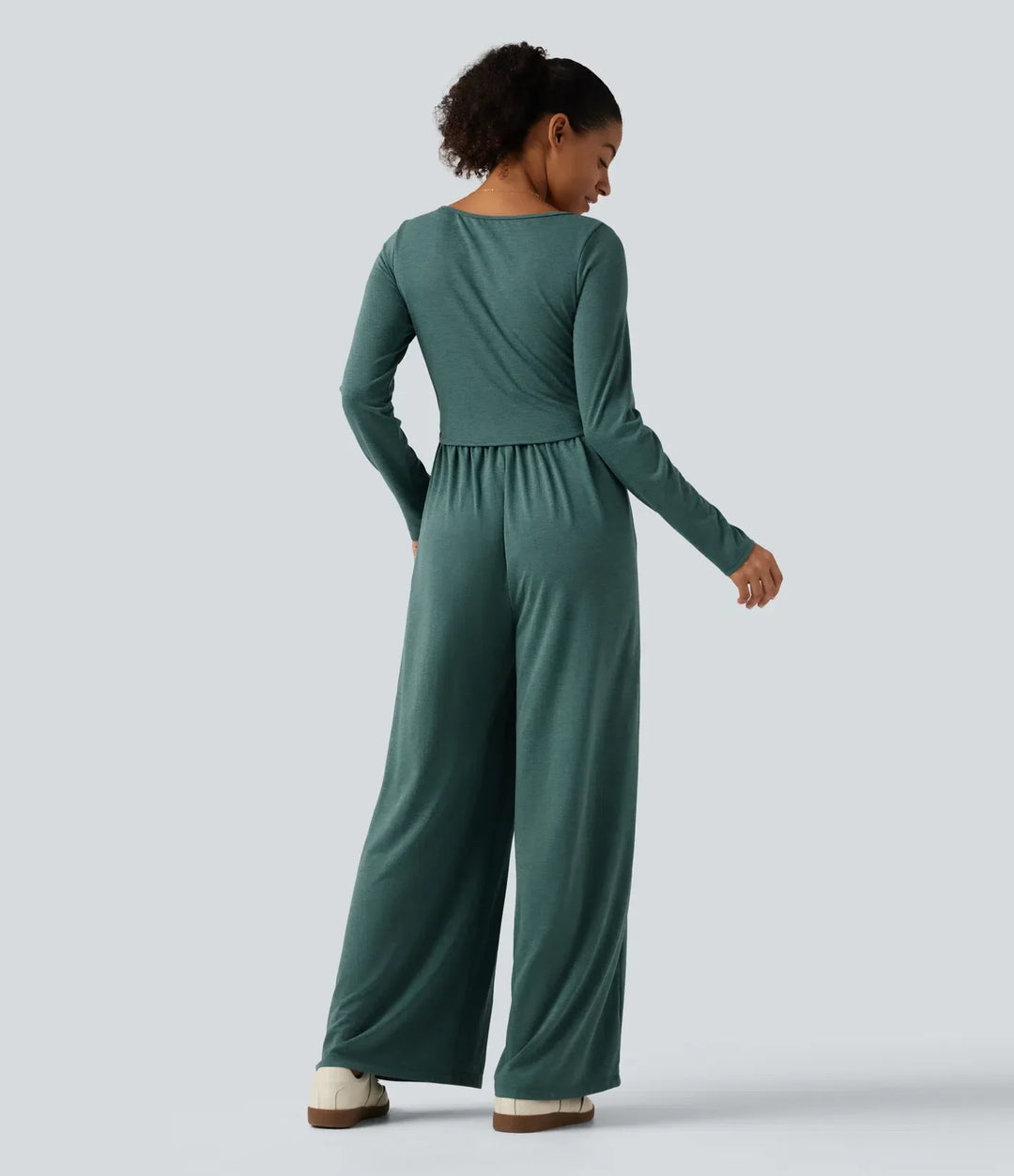 Modell bakifrån i grön långärmad jumpsuit med rynkad midja
