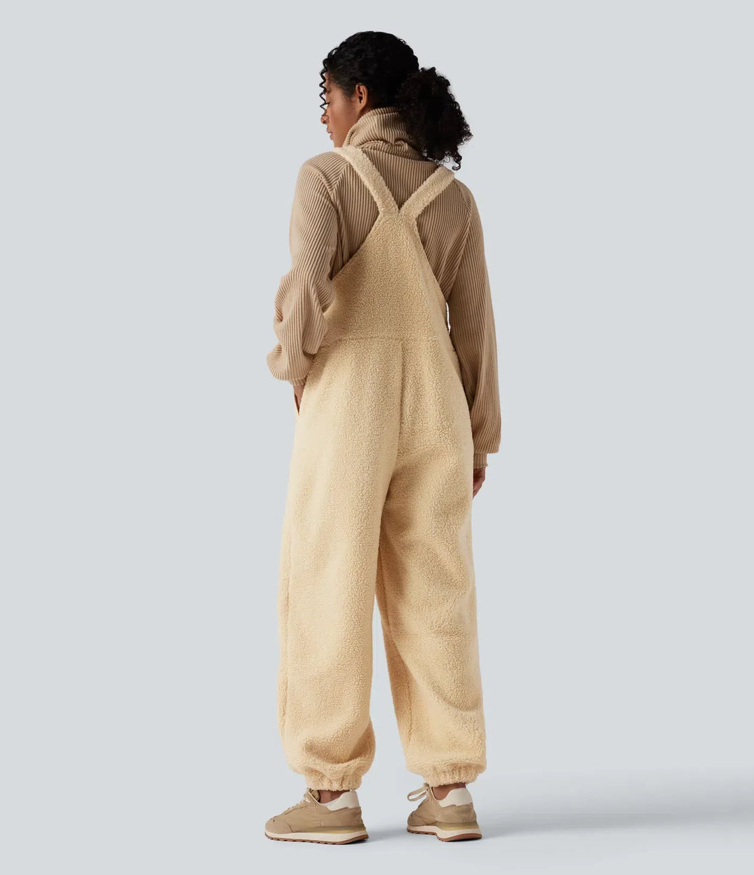 Baksidesvy av dam i beigefärgad sherpaoverall