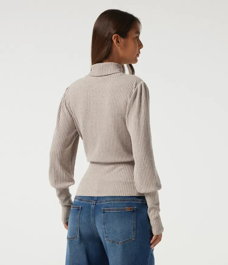Baksida av beige ribbstickad damtopp med hög hals och puffärm på modell