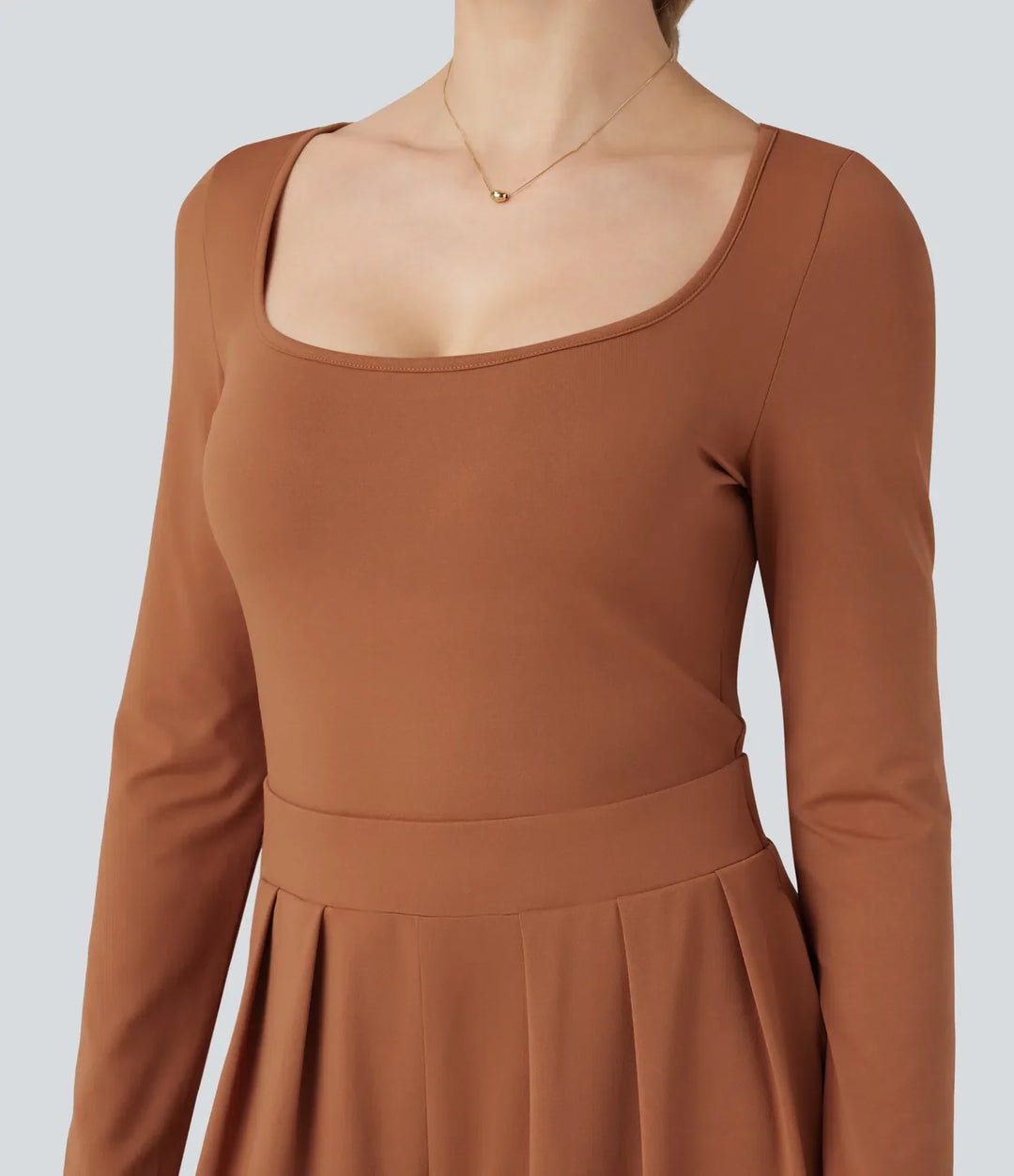 Närbild på u-ringning och tygdetaljer på damjumpsuit med lång ärm