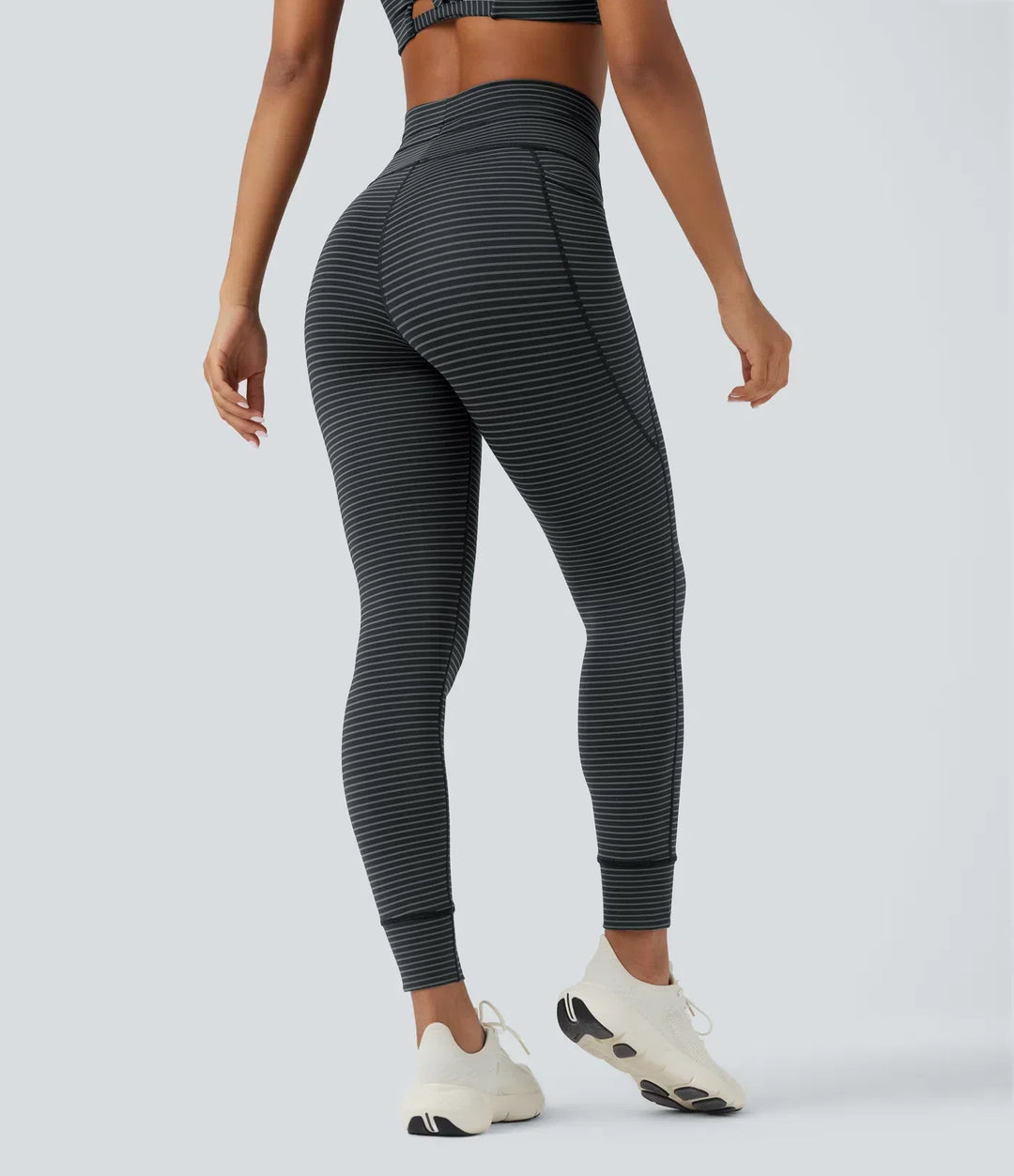 Bakifrån av dam i högmidjad randig yogaleggings med fickor