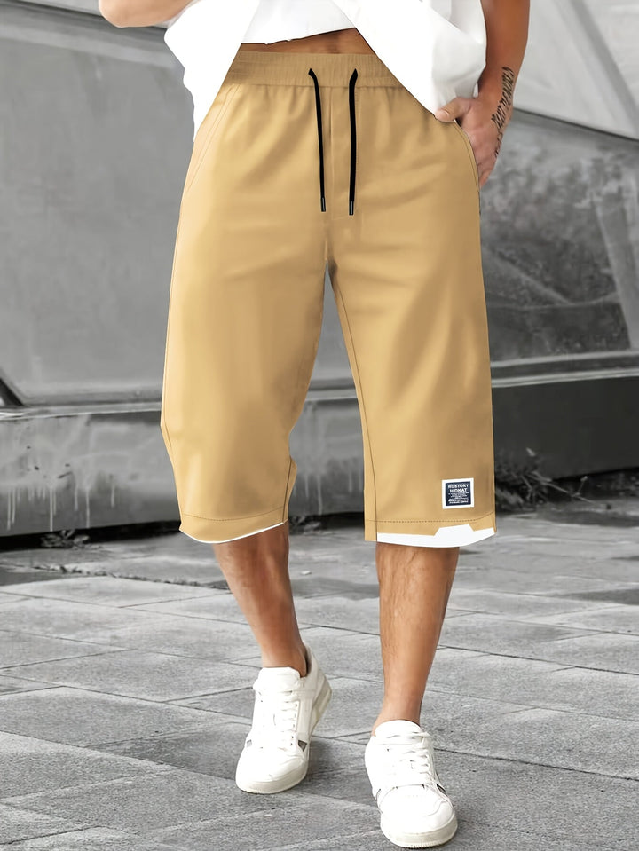 Man bär Weston avslappnade dragsko shorts i khaki färg med vita sneakers