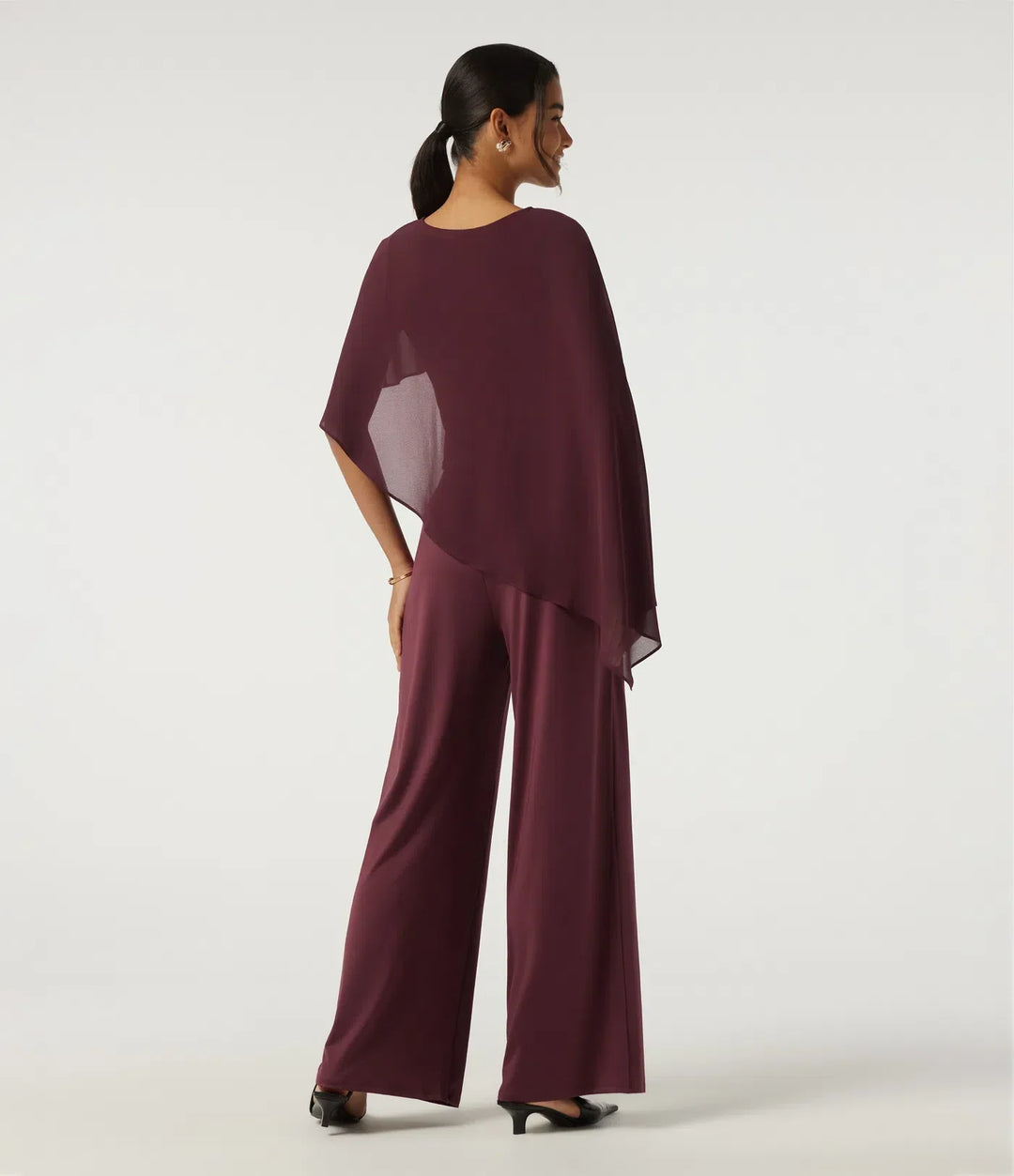 Baksida av den eleganta mörklila asymmetriska damjumpsuiten med vida ben