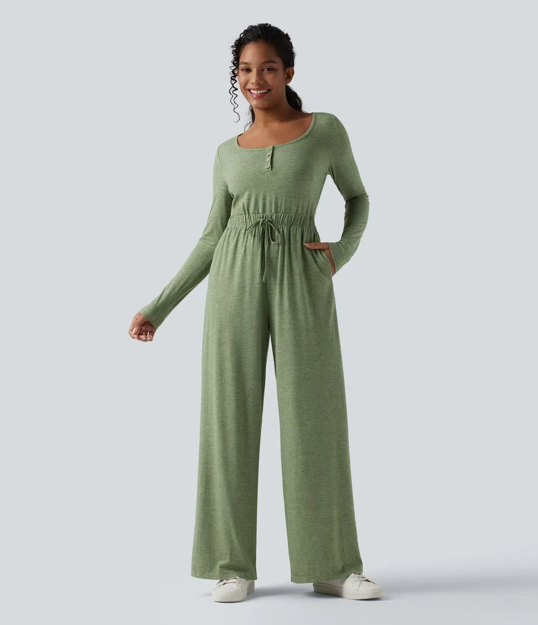 Helhetsbild framifrån av grön långärmad jumpsuit med knäppning upptill