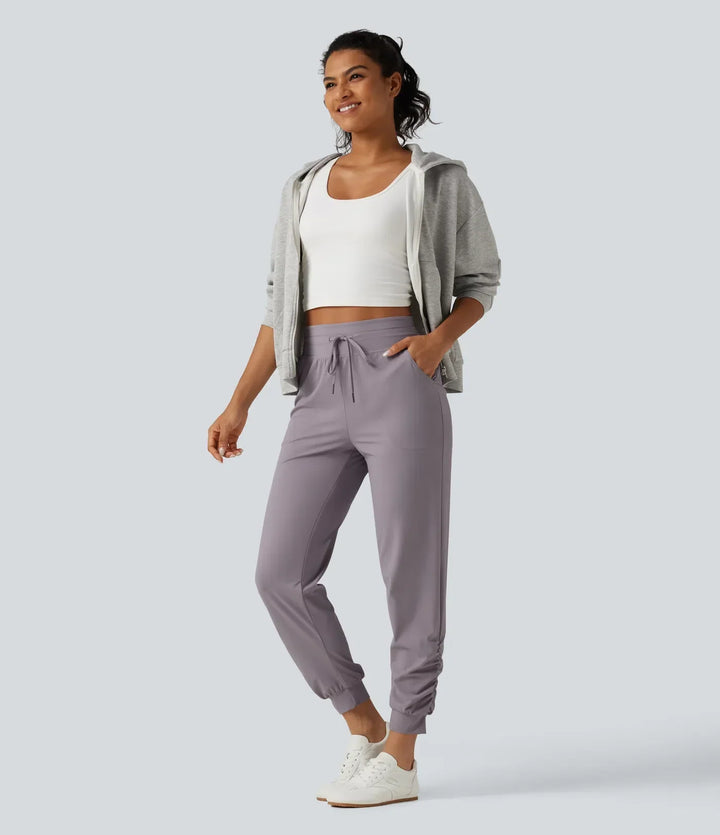 Detaljbild på högmidjade dam joggers med stretch och rynkad design