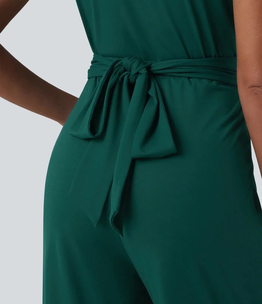 Detaljbild på V-ringning och knytbälte på grön damarbetsjumpsuit