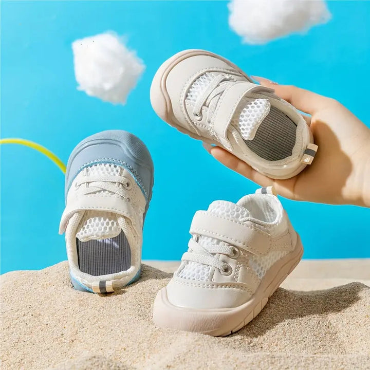 Baby barfotagång sneakers i blå och beige färg som hålls i handen