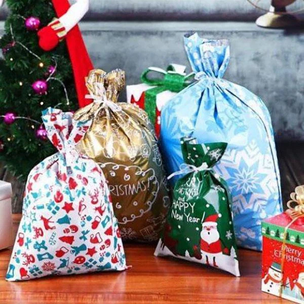 Olika storlekar av julklappspåsar med jultema framför granen