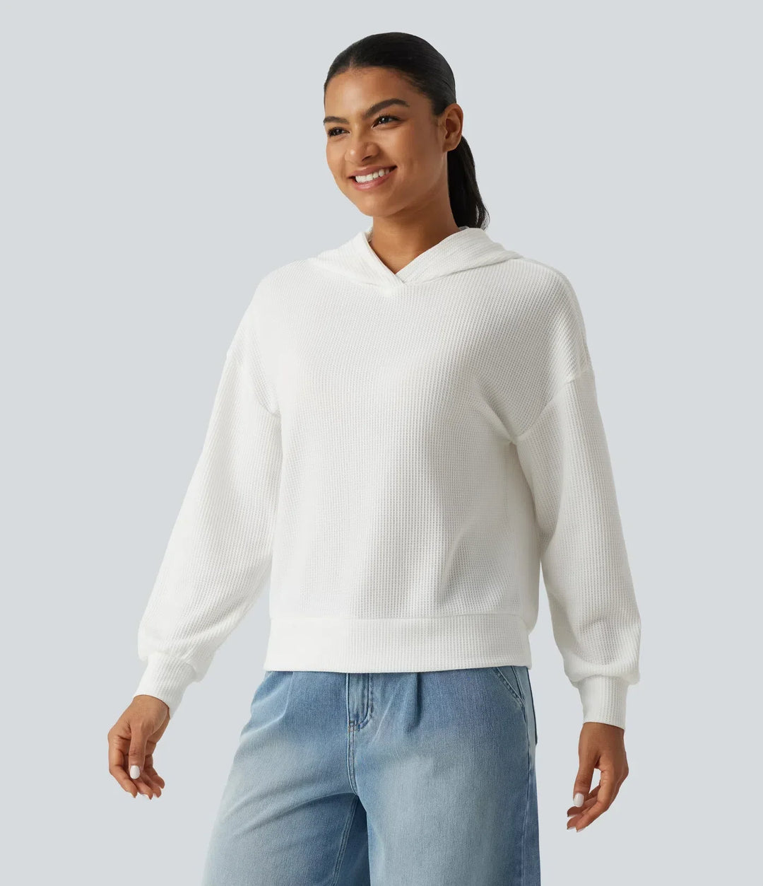 Närbild på kvinna i vit sweatshirt med huva och nedhasade axlar