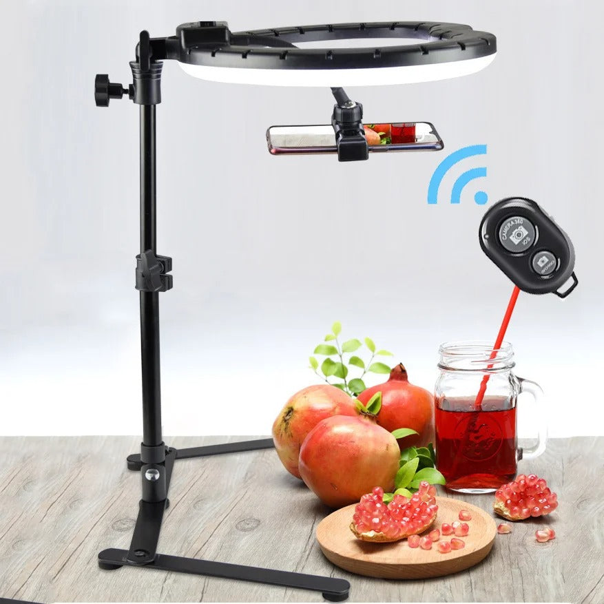 Ring light stativ med telefonhållare uppställt på bord med granatäpplen