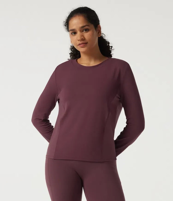 Kvinna iförd mörklila långärmad träningssweatshirt med rund hals och meshdetaljer