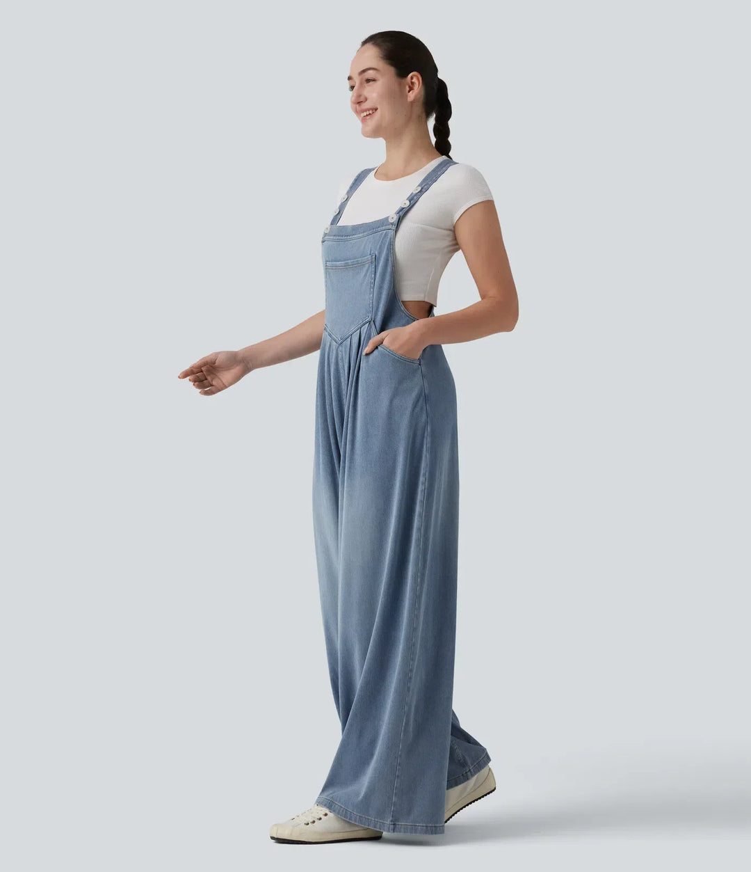 Kvinna i blå draperad baggy overall sedd från sidan