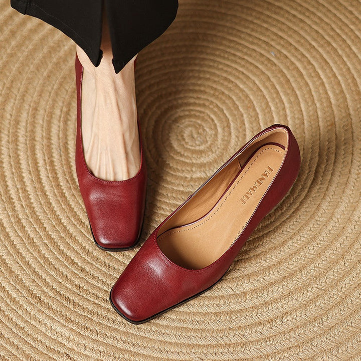 Ovanifrån-vy på eleganta pumps med fyrkantig tå på rund matta
