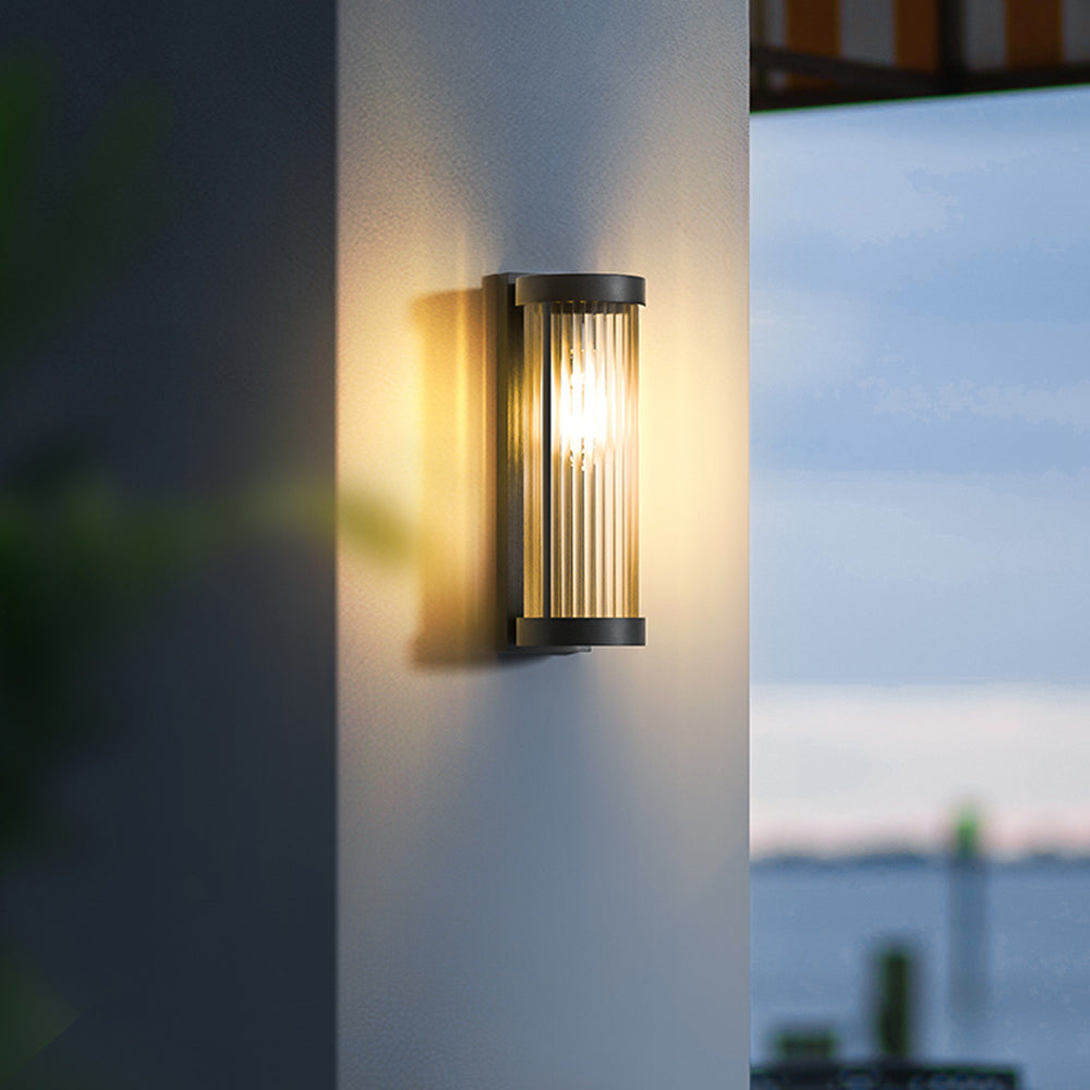 Närbild på tänd cylindrisk solenergidriven utomhuslampa på husvägg