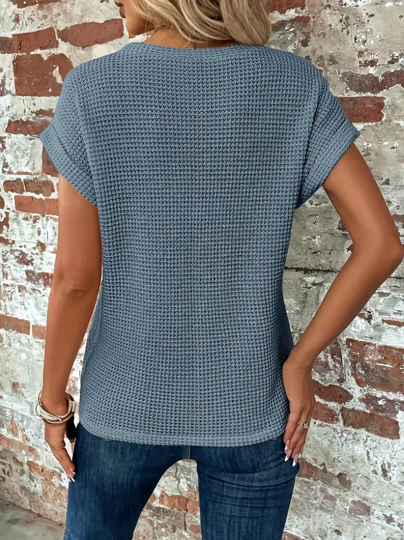 Kvinna i blå sommar-t-shirt bakifrån mot tegelvägg
