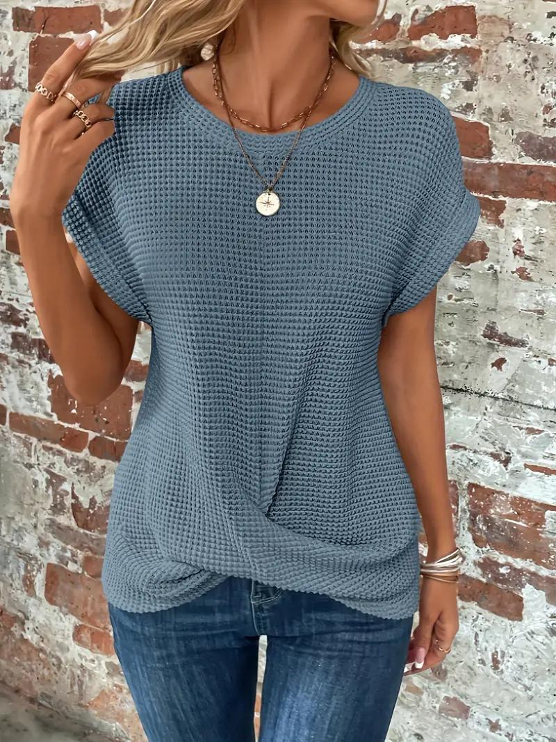 Kvinna i blå sommar-t-shirt i halvprofil mot tegelvägg