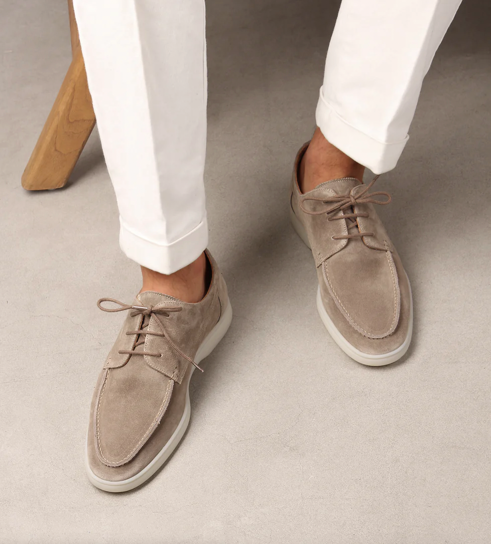 Man som bär eleganta ljusbeige herrskor med vita byxor
