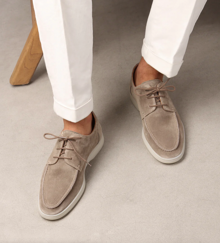 Man som bär eleganta ljusbeige herrskor med vita byxor