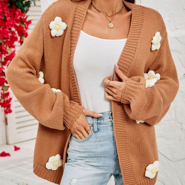 Närbild på stickad damcardigan med dekorativa blomdetaljer
