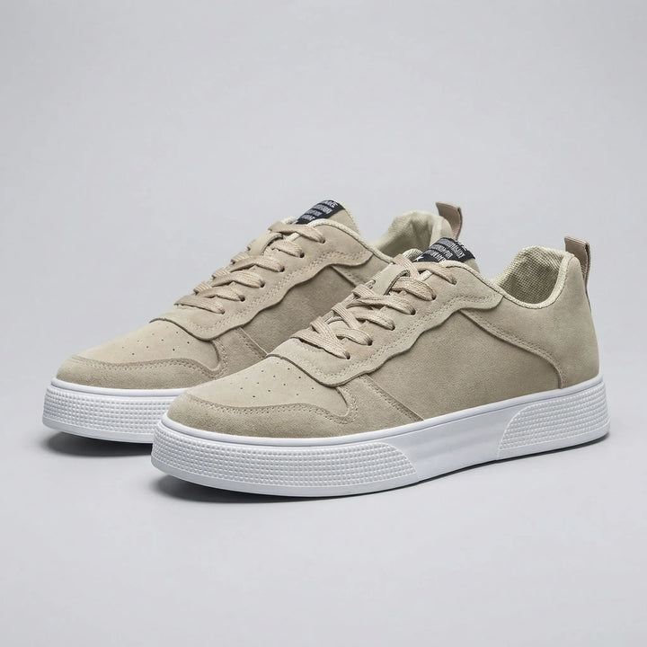 Par beiga låg-top sneakers mot neutral bakgrund