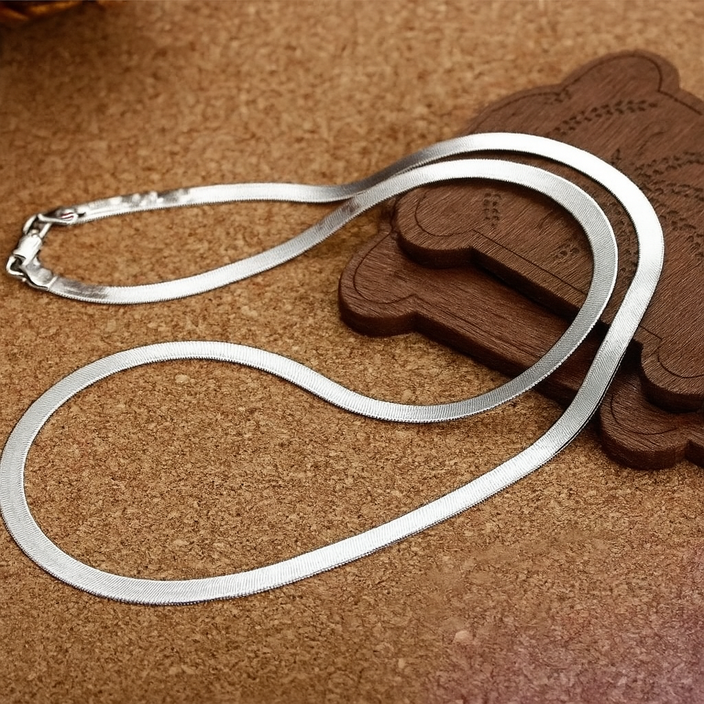 Unisex silverhalsband med bladkedja upplagt på dekorativ yta