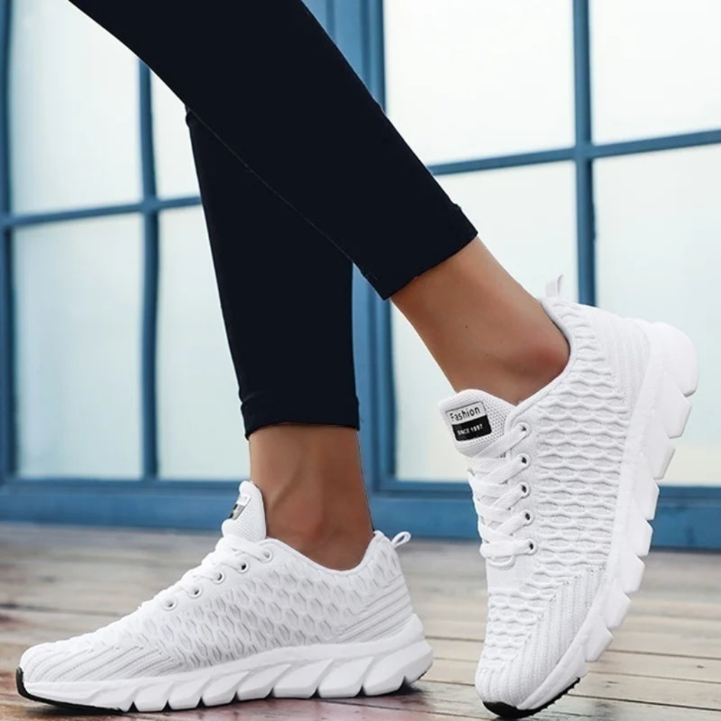 Vita fritidssneakers på modell med svarta byxor