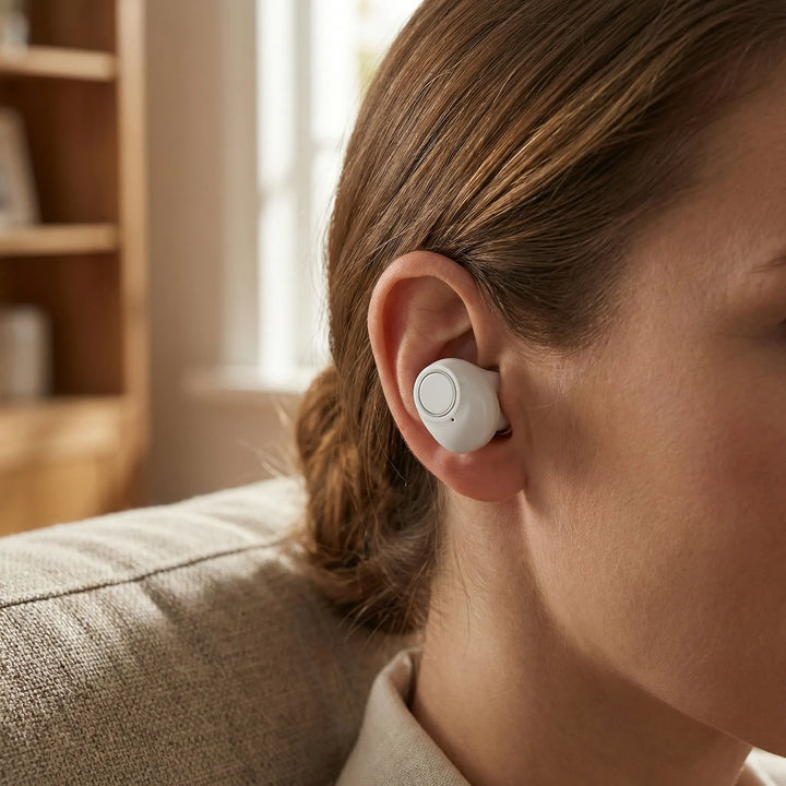 Kvinna som bär en diskret vit in-ear ljudförstärkare