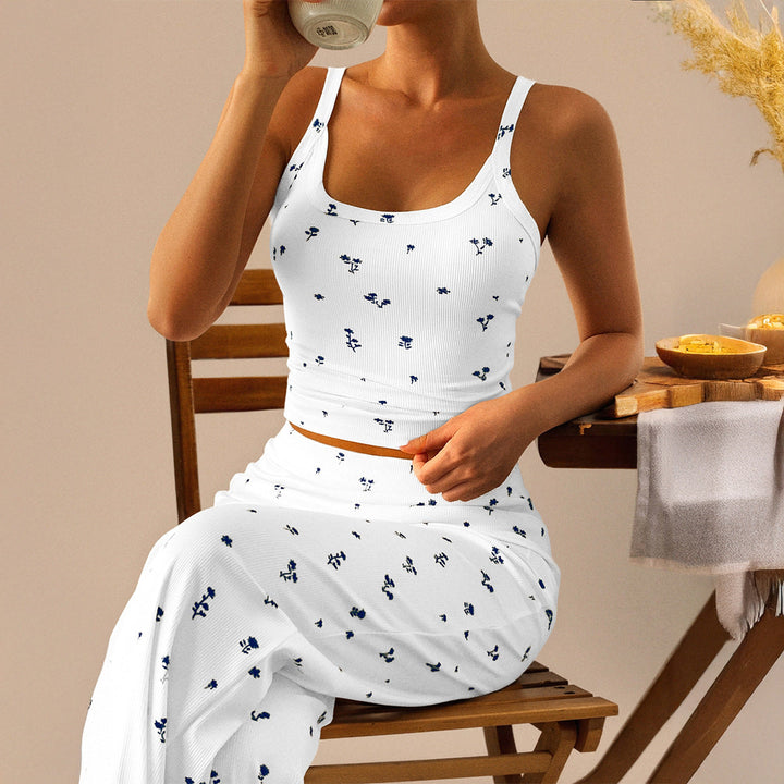 Vit dam pyjamas med blommönster och tunn topp sittande vid bord