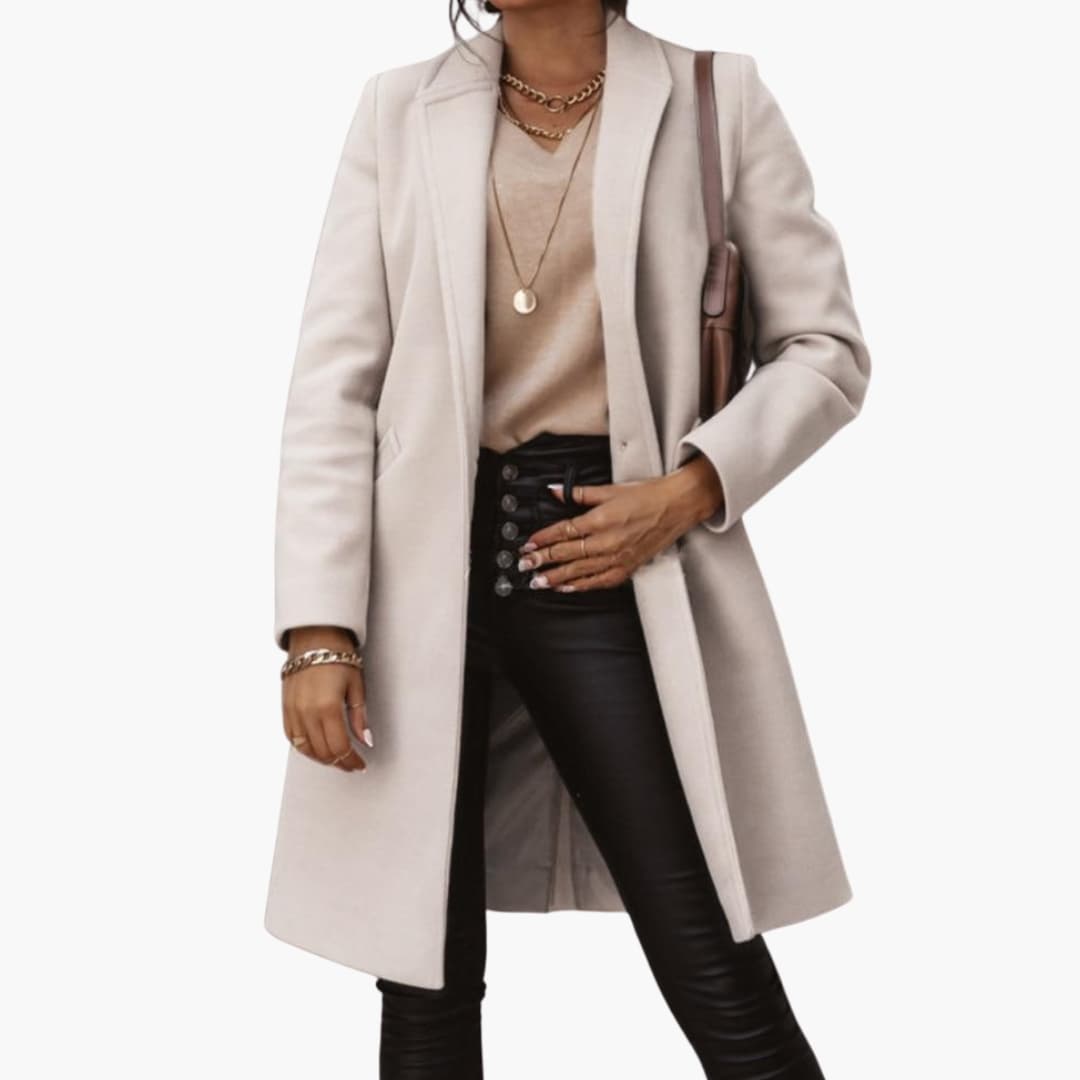 Modell som bär elegant beige lång kappa med svarta byxor