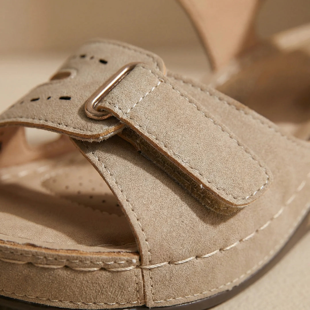 Närbild på den justerbara remmen och detaljerna på den beige sandalen