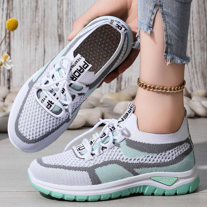 Närbild på vita och gröna ortopediska sneakers med snörning och mönstrad sula