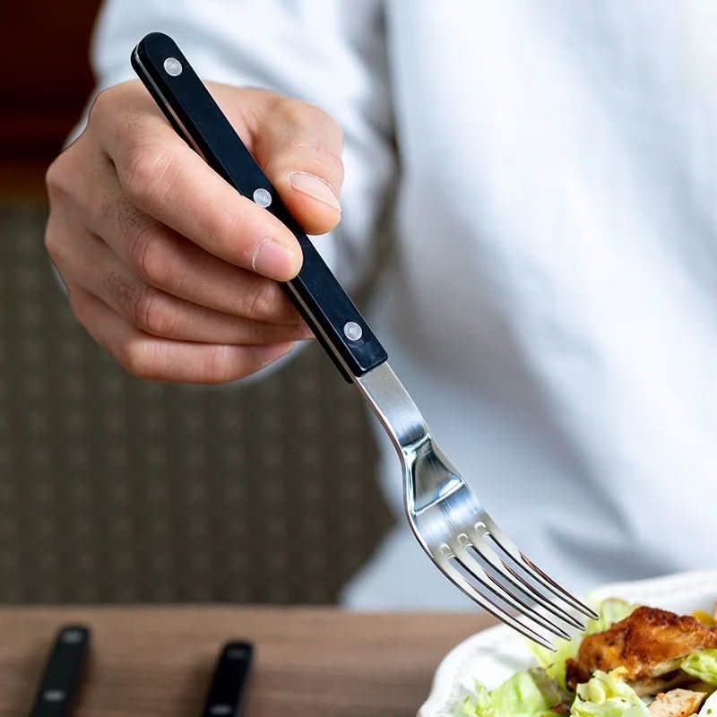 Svart 24-delars bestickset i rostfritt stål med elegant gravyr för dukning