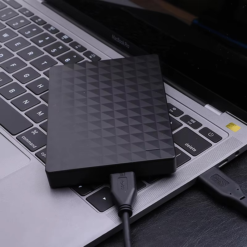 Portabel hårddisk inkopplad med USB-kabel på en bärbar dator