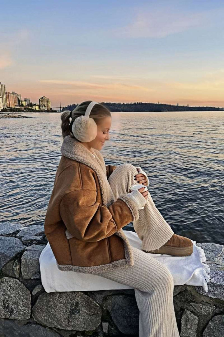 Profilbild av kvinna sittande vid vattnet i varm vinterjacka