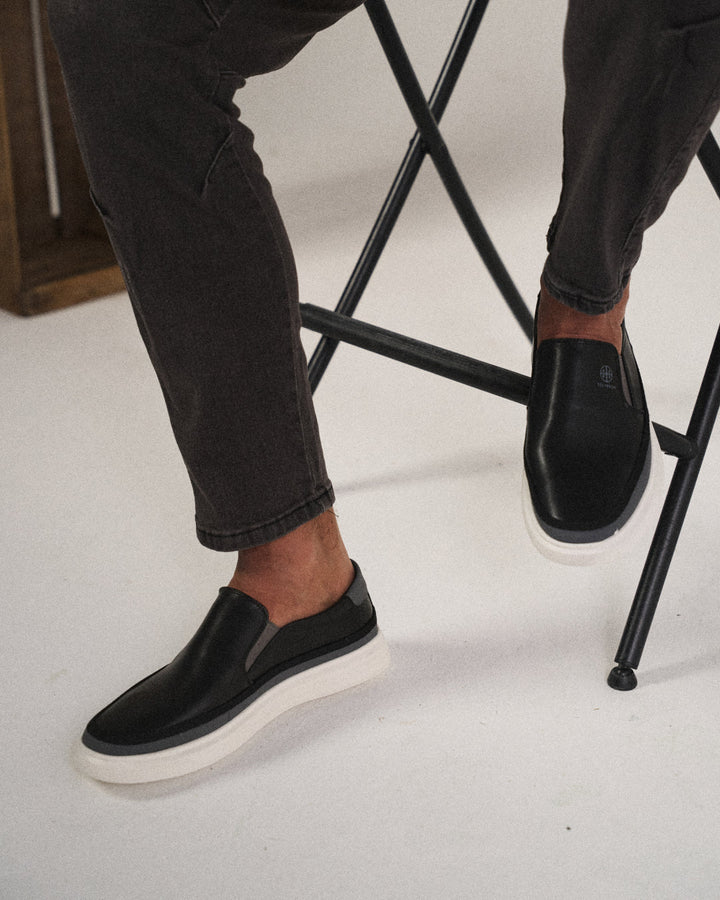 Närbild på ovandelen av svarta slip-on-skor för herrar